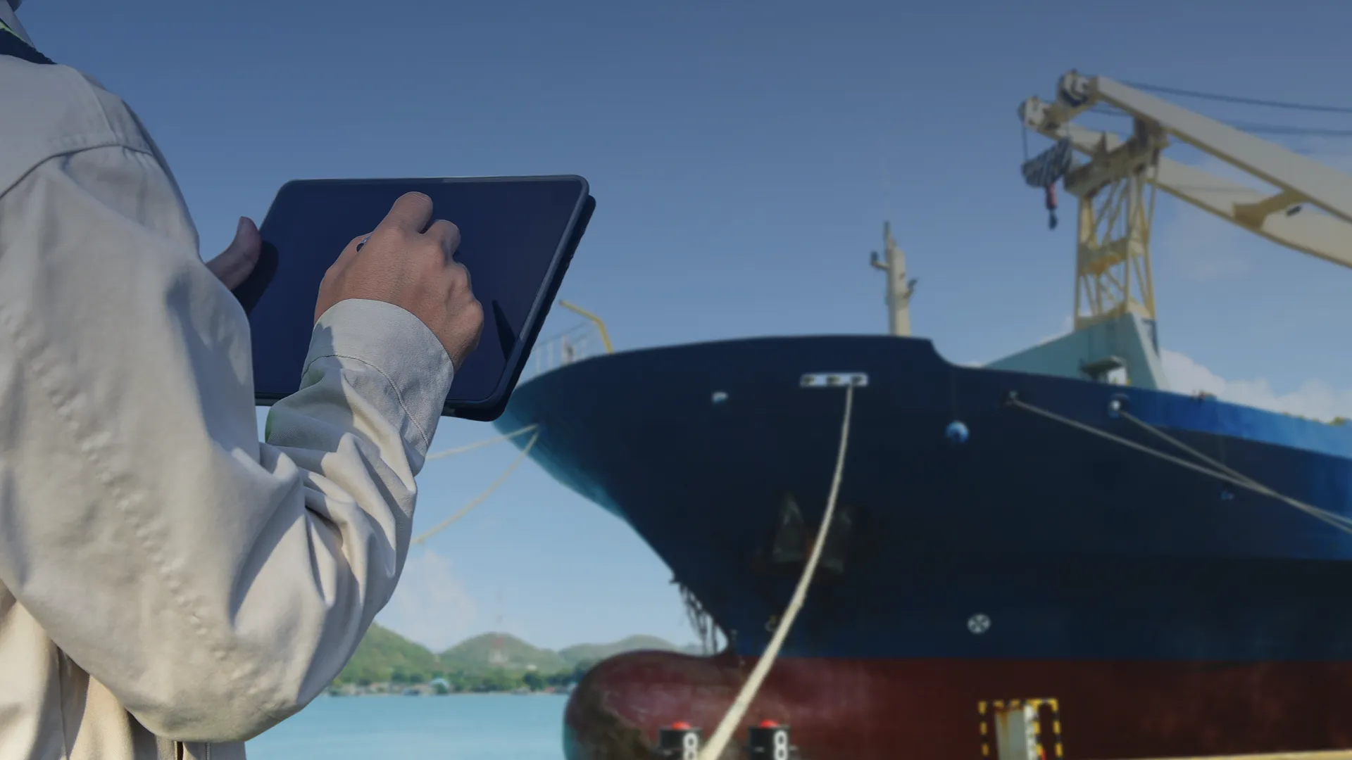 Bemanningslid gebruikt tablet voor chemisch beheersysteem aan boord van een schip, gericht op veiligheid en milieubescherming.